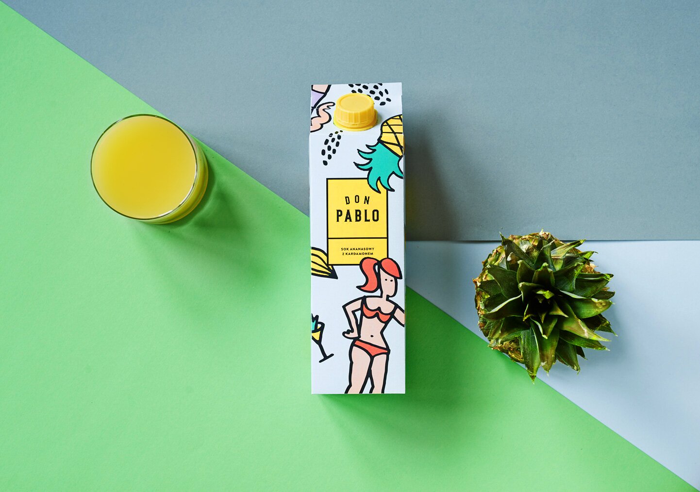 A photography of pineapple juice carton with glass and pineapple